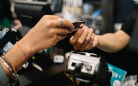 Close-up of hands completing a payment transaction at a retail checkout using a bank card.