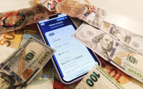 A smartphone displaying a currency converter surrounded by dollar and euro banknotes, highlighting exchange rates.