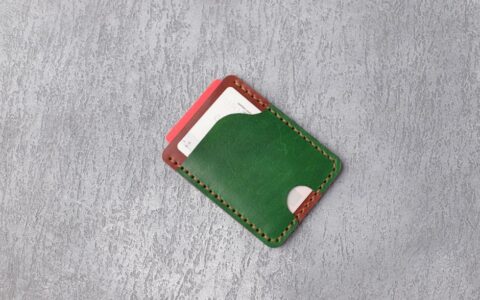 Stylish green leather wallet on textured gray surface showcasing minimalistic design.