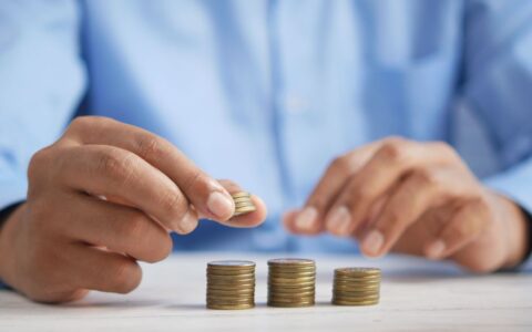 Close-up of hands stacking gold coins, symbolizing financial growth and savings.